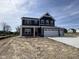 Charming two-story home with navy blue siding, white trim, red door and a spacious three-car garage at 338 Mcnair Dr, Whiteland, IN 46184