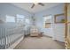 A Bedroom with light blue walls featuring a crib, chair, and dresser with charming decor and three windows at 357 Parkway Ave, Indianapolis, IN 46225