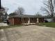 Red brick single-story home features a wooden back deck and a concrete slab for parking or sports at 5209 S Bancroft St, Indianapolis, IN 46237