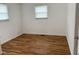 Cozy bedroom with hardwood flooring, white walls, and natural light from two windows at 5209 S Bancroft St, Indianapolis, IN 46237