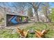 Backyard with two Adirondack chairs and a fire pit sitting on a lush lawn by the painted shed at 6153 Evanston Ave, Indianapolis, IN 46220