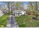 Charming cottage-style home featuring a well-manicured lawn, quaint walkway, and an American flag on the front porch at 6153 Evanston Ave, Indianapolis, IN 46220