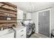Laundry room with a stacked washer and dryer, a decorative wood panel wall and a stylish chandelier at 6153 Evanston Ave, Indianapolis, IN 46220