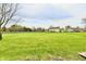 Expansive backyard with lush green grass, mature trees, and a glimpse of neighboring houses at 6591 Rushing, Noblesville, IN 46062