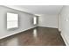 Empty living room with three windows, baseboard trim and dark laminate flooring at 6591 Rushing, Noblesville, IN 46062