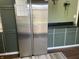 A view of the stainless steel fridge inside the kitchen with green painted cabinets and wooden flooring at 760 E Walnut St, Martinsville, IN 46151
