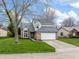 Charming two-story home with brick accents, attached garage, and well-manicured lawn and mature trees at 7775 Hollow Ridge Cir, Indianapolis, IN 46256