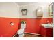 Cozy bathroom with red wainscoting, a toilet, sink, and decorative accents at 840 Cottage Ave, Indianapolis, IN 46203