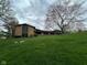 Home with stone and wood exterior, complemented by a lush green lawn and mature trees against a cloudy sky at 8801 Ridge Hill Dr, Indianapolis, IN 46217