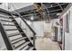 Unfinished basement with water heater and black stairs leading to the upper level at 936 N Oxford St, Indianapolis, IN 46201