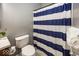 Cozy bathroom features blue striped shower curtain, white toilet, and gray walls at 11648 Stickney Ct, Fishers, IN 46037