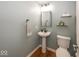 Elegant powder room features a pedestal sink, a stylish mirror, and hardwood floors at 11648 Stickney Ct, Fishers, IN 46037