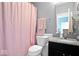 Bathroom with pink shower curtain, black cabinet with marble top, and neutral gray walls at 1243 Colinbrook Cir, Greenwood, IN 46143
