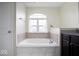 Bathroom featuring a luxurious soaking tub, granite countertops, and an arched window for natural light at 1243 Colinbrook Cir, Greenwood, IN 46143