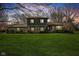 Beautifully lit home showcasing its stone accents and expansive green lawn at dusk at 13892 Adios Pass, Carmel, IN 46032