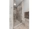 Modern bathroom shower featuring gray stone tile surround, glass door, and mosaic tile floor at 13892 Adios Pass, Carmel, IN 46032