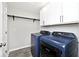 Modern laundry room featuring a blue washer and dryer, cabinets and a shelf for extra storage at 15341 Montfort Dr, Noblesville, IN 46062