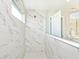 Modern shower featuring marble-style tiling, glass partition and a view of vanity and mirror at 15341 Montfort Dr, Noblesville, IN 46062
