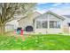 View of the backyard showcasing the sunroom, patio, and lush green lawn at 1614 Ashley Dr, Lebanon, IN 46052
