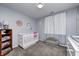 Bedroom room features a crib, gray walls with floral decor, curtains and a small chair at 1614 Ashley Dr, Lebanon, IN 46052