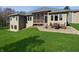 Exterior view of the home showcasing a stone patio and well-maintained lawn with mature trees at 1995 Brookfield Ct, Columbus, IN 47201