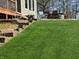 Backyard with grass and garden area, featuring wood steps leading to a patio with outdoor furniture at 1995 Brookfield Ct, Columbus, IN 47201