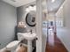 Stylish half bathroom featuring a pedestal sink, decorative mirror, and a view down a bright hallway at 1995 Brookfield Ct, Columbus, IN 47201