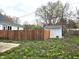 Large backyard featuring a wooden fence and storage shed, surrounded by green grass and blooming flowers at 212 W Burnside Ave, Fairland, IN 46126