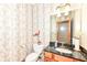 Bathroom with patterned wallpaper, a dark vanity, and a decorative mirror at 2446 Quiet Way, Indianapolis, IN 46239