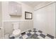 Bathroom with blue checkered floors, white wood-panel walls, and featuring a toilet, mirror, and cabinet at 282 N Mapleton St, Columbus, IN 47201