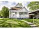 A charming two-story home with a covered porch and a well-manicured front lawn, surrounded by lush greenery at 3031 Nowland Ave, Indianapolis, IN 46201
