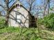 Exterior of a small cottage-style building surrounded by greenery and scaffolding, adding a unique charm to the property at 324 E Burgess Ave, Indianapolis, IN 46219