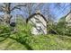 Quaint shed with decorative gable detail, surrounded by overgrown greenery and construction scaffolding at 324 E Burgess Ave, Indianapolis, IN 46219