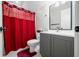 A lovely bathroom featuring gray cabinets, a white toilet, and a red shower curtain at 3331 Daniel St, Mooresville, IN 46158