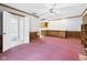 Spacious living room featuring pink carpet, wood paneling, built-in shelves and kitchen access at 3629 Woodglen Way, Anderson, IN 46011