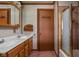 Bathroom featuring double sinks, a storage cabinet, and a shower with glass doors at 426 Oakwood Dr, Indianapolis, IN 46260