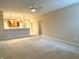 Bright, open-concept living room featuring neutral carpeting, ceiling fan, and access to the kitchen area at 4327 Switchgrass Way, Indianapolis, IN 46237