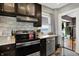 Kitchen features stainless appliances, marble countertop, dark cabinetry, with door to another room at 433 Eastern Ave, Indianapolis, IN 46201