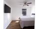 Inviting bedroom with a ceiling fan, a large window with blinds, a wall-mounted TV, and hardwood floors at 4421 Greenmeadow Ct, Indianapolis, IN 46235