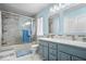 Bathroom featuring double sinks, marble countertops, and a shower/tub combo with glass doors at 4922 Birmingham Dr, Indianapolis, IN 46235