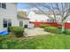 A well maintained backyard with a brick patio, green grass, manicured shrubbery and red wooden fence at 5817 Thompson Park Blvd, Indianapolis, IN 46237