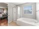 Bright bathroom showcases tub with shower and glass door adjacent to main bedroom at 5817 Thompson Park Blvd, Indianapolis, IN 46237