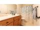 Bright bathroom has wood vanity, sink, toilet, and shower with a patterned curtain at 6081 Boulder Ct, Columbus, IN 47201