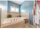 Bright bathroom features a soaking tub with neutral tiling, and an open window for natural light at 6081 Boulder Ct, Columbus, IN 47201
