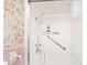 Clean bathroom featuring a shower with safety bars and floral wallpaper at 6454 Dean Rd, Indianapolis, IN 46220