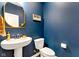 Stylish powder room featuring a modern pedestal sink, blue walls, and gold accents, creating a chic space at 6622 Cardiff Cir, McCordsville, IN 46055