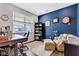 Cozy home office with a large window, dark wood desk, comfy chair, and blue accent wall with decor at 6622 Cardiff Cir, McCordsville, IN 46055