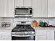 Close-up of a modern kitchen with white cabinets, stainless steel appliances, and a subway tile backsplash at 6622 Cardiff Cir, McCordsville, IN 46055