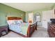 Green bedroom featuring a wooden bed frame, bedside table, closet, and doorway leading to another room at 7048 Tassel Meadow Dr, Indianapolis, IN 46217