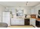 Well-lit kitchen with white cabinets, black appliances, and an opening view to the living area at 7048 Tassel Meadow Dr, Indianapolis, IN 46217